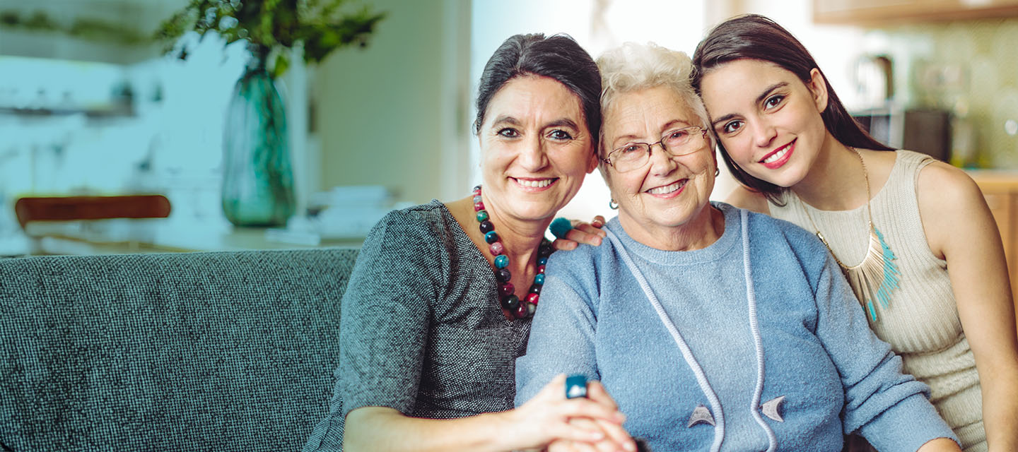 Photo of three generations of women hugging all smiling