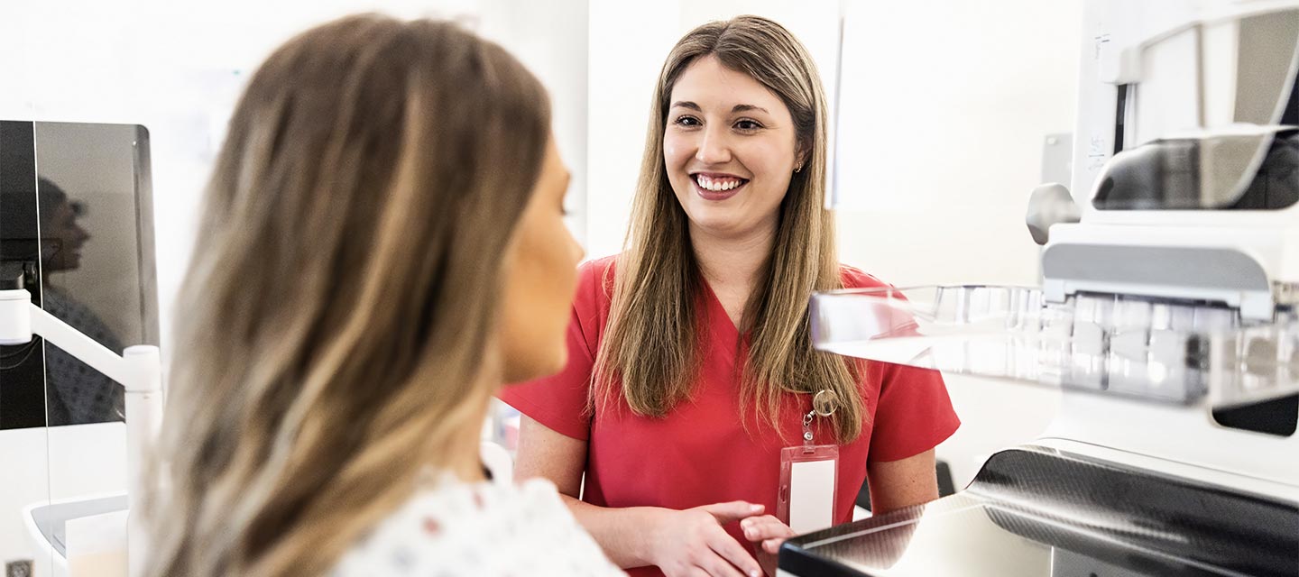 Nurse preparing female patient for mammogram in doctor's office