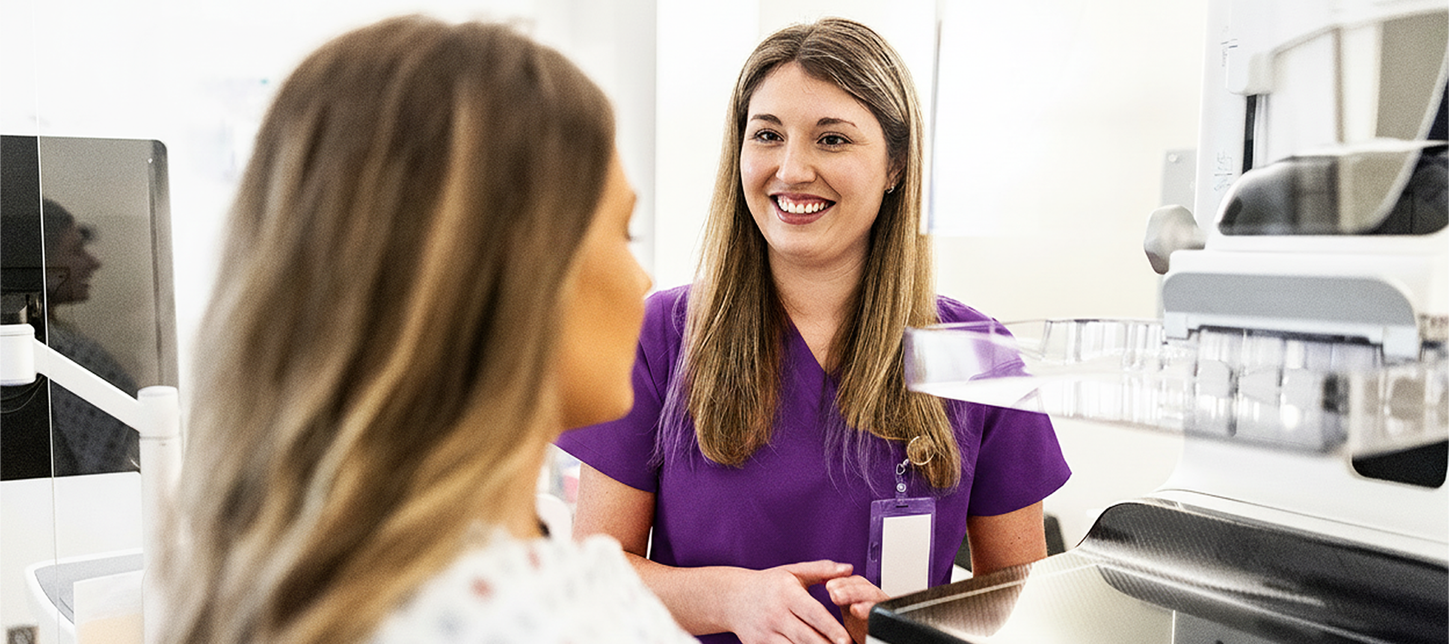 Nurse preparing female patient for mammogram in doctor's office