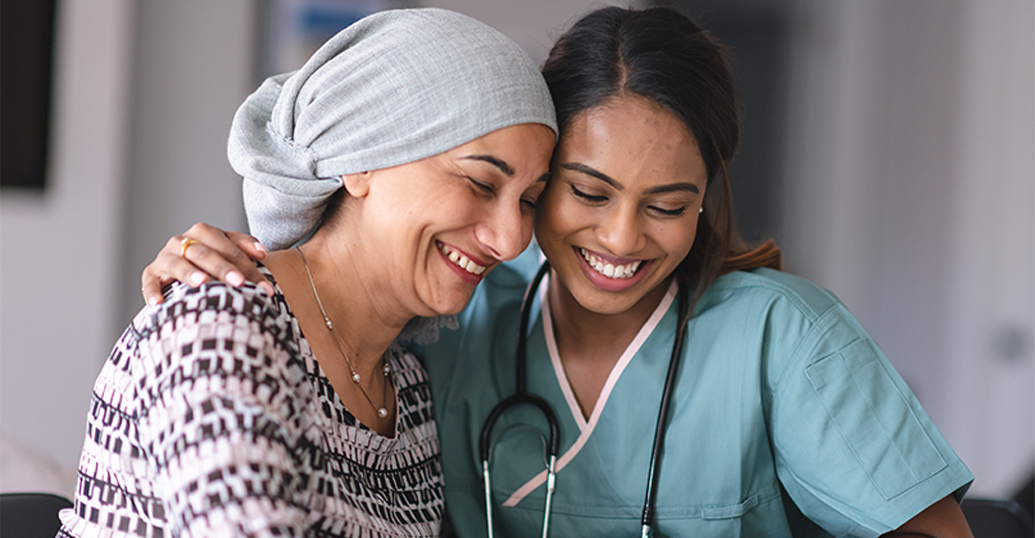 Female cancer patient hugging her female physician, smiling