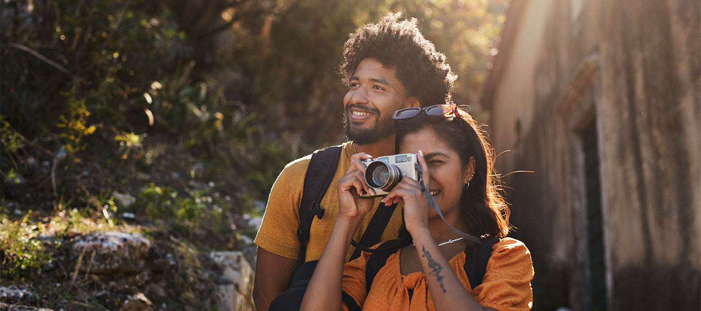 Couple walking in the woods with the woman taking a photo