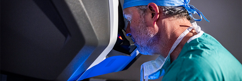 Male surgeon sitting at surgical robotic console